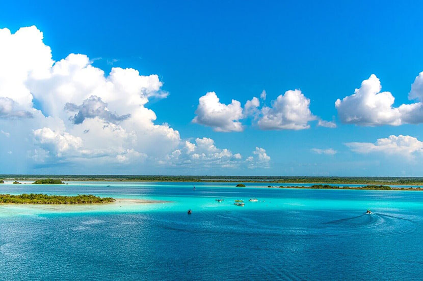 Laguna de Bacalar com águas azul-turquesa e tons cristalinos, rodeada por natureza tropical.