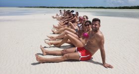 Pessoas a posar em Punta Mosquito, com águas rasas e paisagem paradisíaca ao fundo.