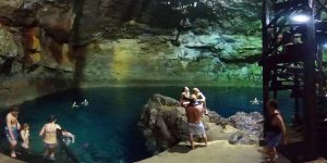 Visitantes a mergulhar no Cenote Choo-Ha rodeado de rocha calcária