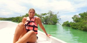 Mulher numa lancha na Reserva da Biosfera de Sian Ka'an, navegando por águas turquesa rodeadas de natureza.